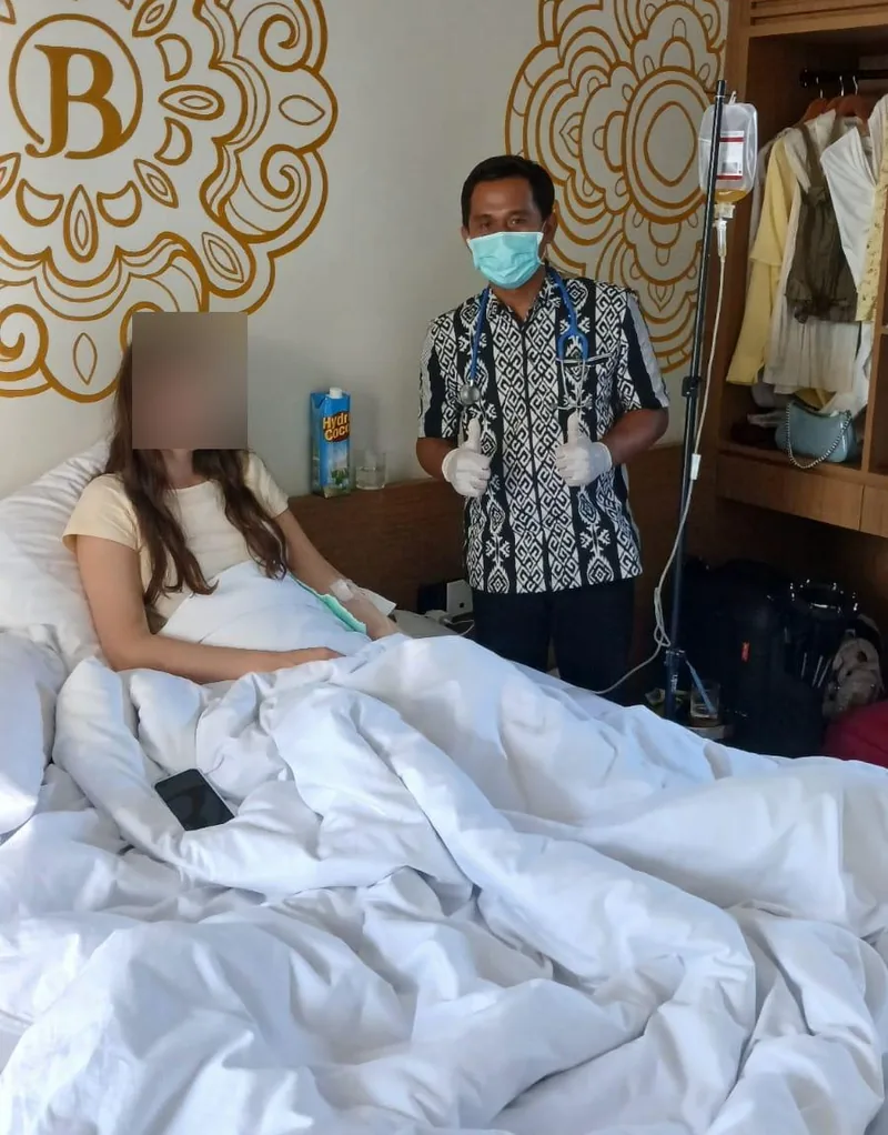 Doctor attending a guest with an IV drip in a hotel suite in Bali, guest's face obscured